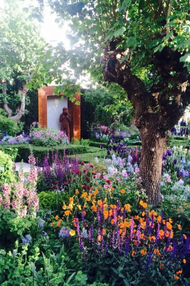 exemple amenagement jardin cure massif de fleurs colorées arbre statue inspiration 