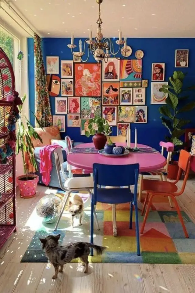 caractéristique décoration maximaliste salle à manger mur bleu électrique table rose chaises dépareillées couleur galerie murale rideau motif 