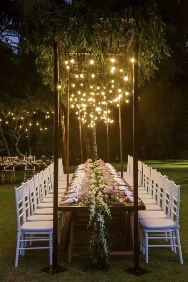 decoration mariage plein air exterieur structure au dessus de la table avec feuillage et luminaire éclairage chic et élégant 20 convives chemin de table fleuri 