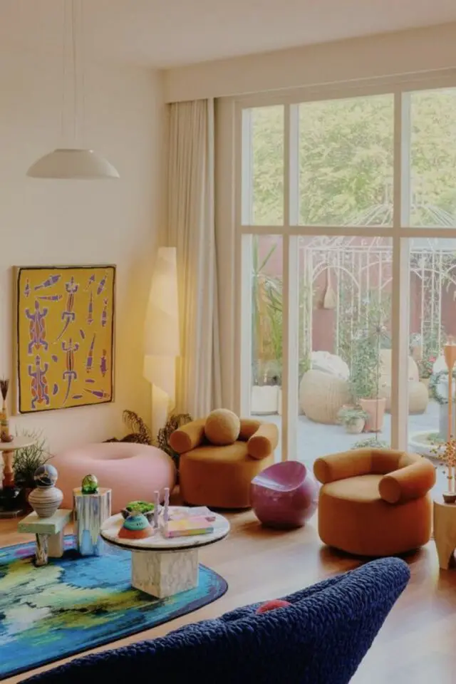 intérieur style maximaliste design exemple séjour salon fauteuil vintage arrondi tapis bleu table basse en marbre grande baie vitrée mur neutre 