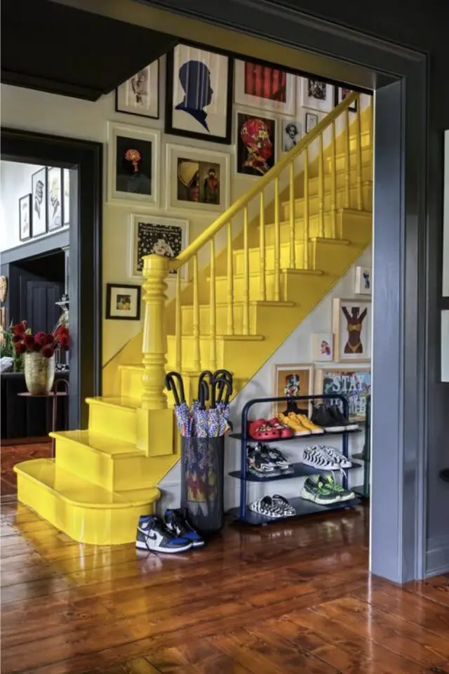 intérieur style maximaliste design entrée avec escaliers peints en jaune petit meuble à chaussure galerie de cadre porte-parapluie 