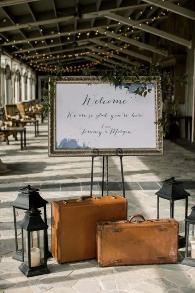 mariage theme voyage exemple panneau de bienvenue salle de réception valise ancienne et lampe à poser 