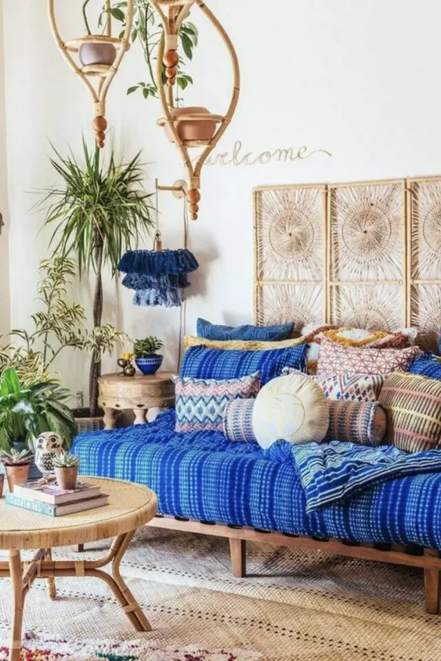 Adopter deco style oriental chez soi salon séjour banquette bleue mur blanc coussin motif paravent tressé petite table basse tapis 