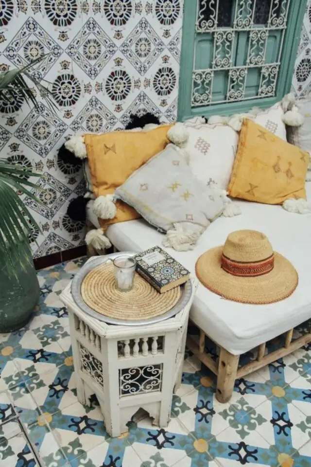 Adopter deco style oriental chez soi salon banquette en bois coussins ethniques jaune et écru mur carrelage sol carreaux de ciment motif 