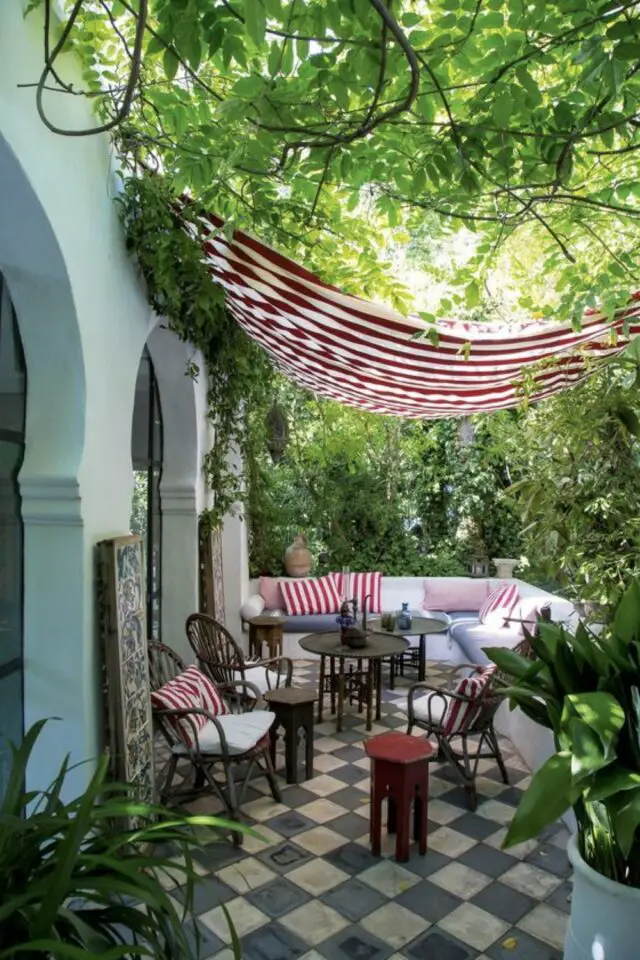 terrasse couverte moderne exemple voile d'ombrage rouge et blanche à rayure style mauresque canapé d'angle extérieur blanc espace verdoyant 