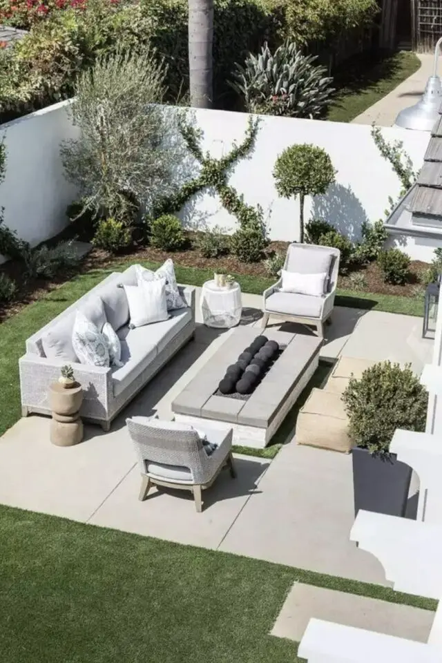 terrasse moderne en béton exemple avec jardin pelouse salon de jardin canapé fauteuil en résine grise grande table basse extérieure pouf arbuste en pot massif de plantes 