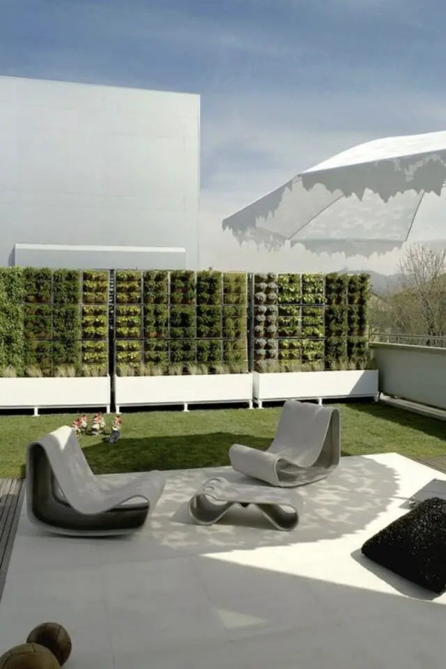terrasse moderne en béton exemple simple et chic associé à de la pelouse clôture végétale mobilier extérieur fauteuil design 