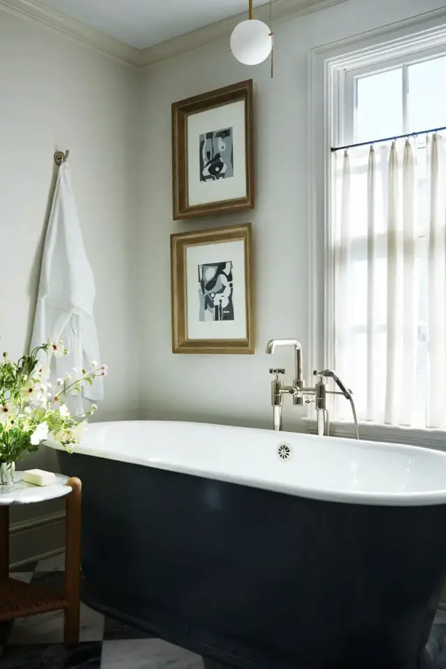 rénovation maison 1900 lumineuse salle de bain avec boignoire ancienne sur pied peinture blanc et noir élégant cadres reproduction tableau 