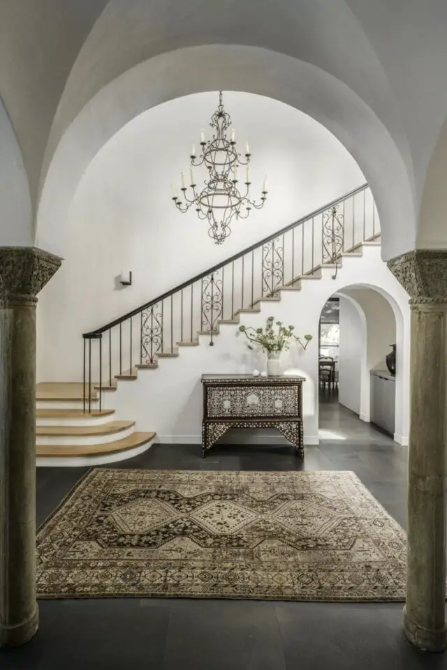 intérieur maison style néo colonial espagnol entrée maison hall avec arche et poteaux escaliers ouverts rampe en fer forgé 