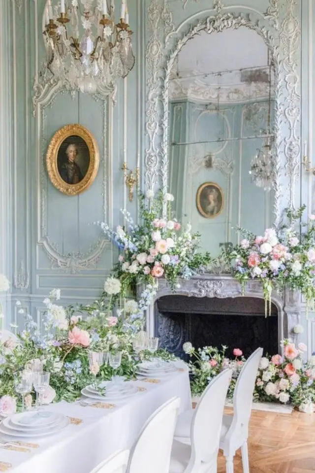 mariage thème Bridgerton regency décoration salle chateau grand miroir cintré dessus cheminée en marbre bouquets de fleurs décor de table invité