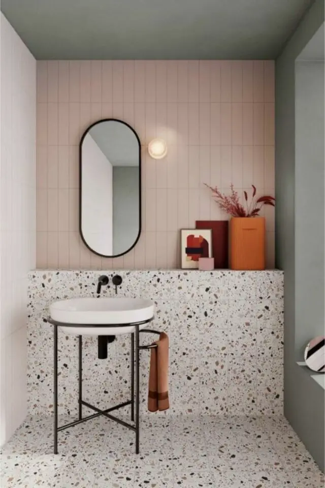 petite salle de bain élégante et moderne carrelage rose clair soubassement et sol en terrazzo lavabo armature métal noir miroir ovale  