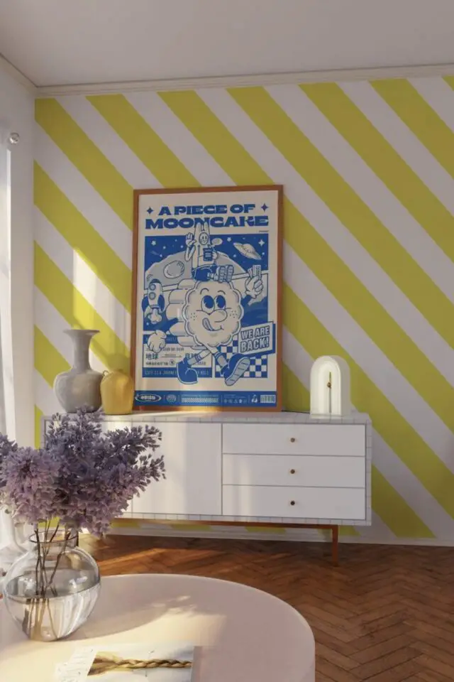 décoration murale salon moderne papier peint rayures obliques jaune et blanc affiche bleu électrique dessus petit buffet 