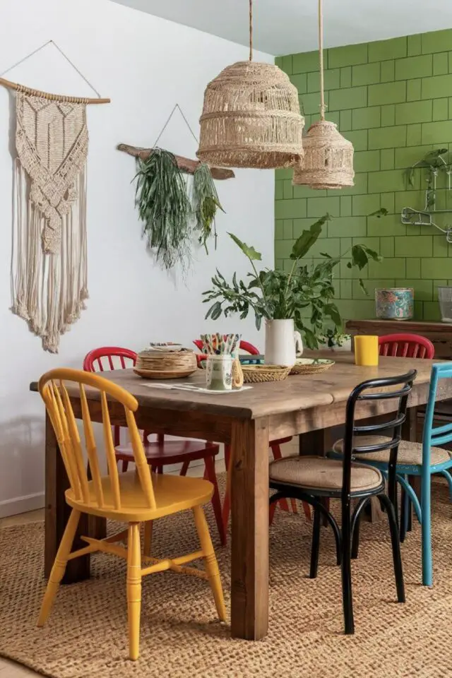 décoration salle a manger table en bois ancienne avec rallonge chaises dépareillées et colorées mur accent vert luminaire naturel et déco murale en macramé 