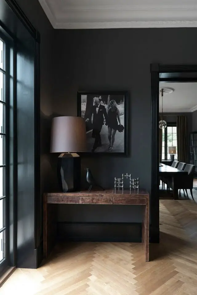 les couleurs sombres sont elles encore tendance 2025 entrée mur gris anthracite console en bois foncé photo noir et blanc encadré luminaire abat-jour marron 