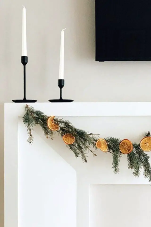 décor cheminée noël tradition minimaliste guirlande sapin et orange séchée bougie élégante avec bougeoir noir 