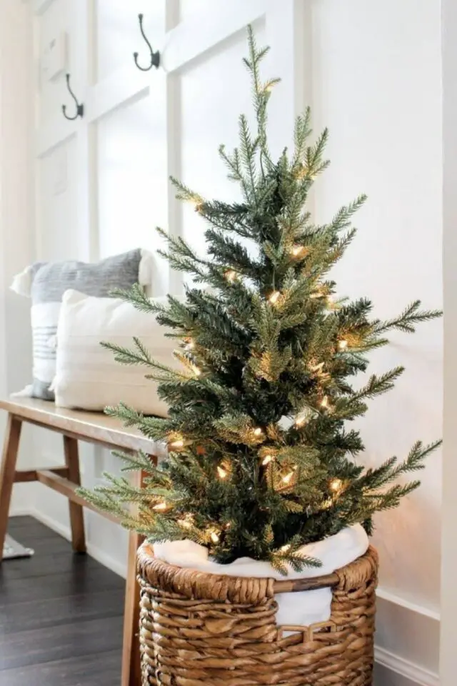 petit sapin de noël exemple décoration arbre miniature panier en rotin guirlande lumineuse entrée banc en bois coussin neutre peinture mur blanc 