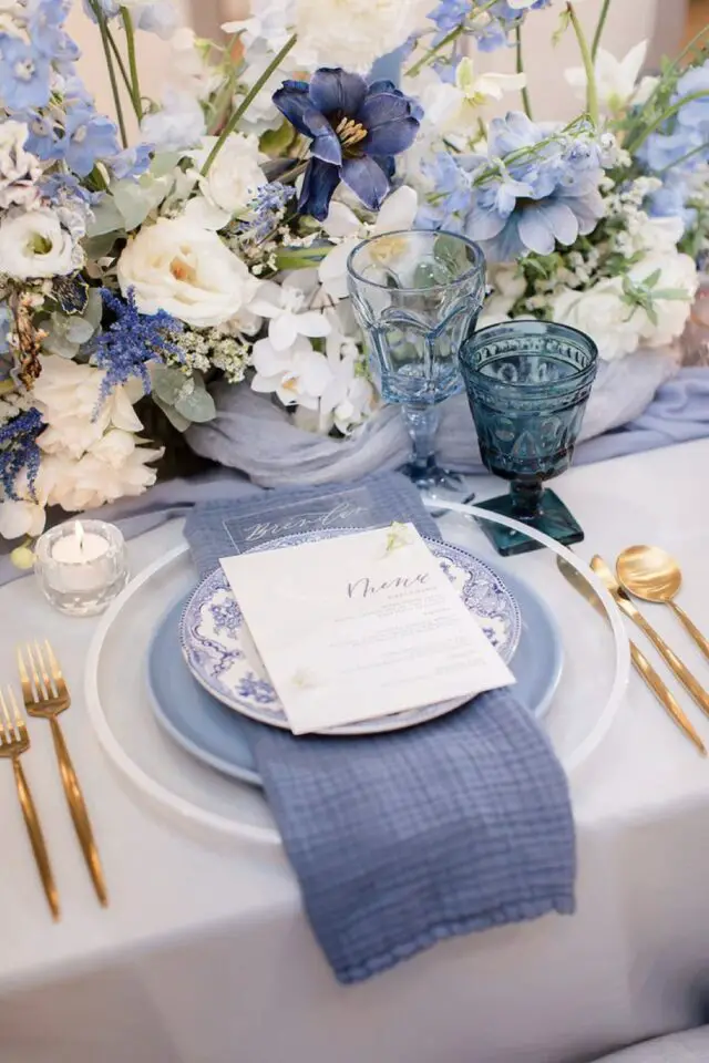 décoration de mariage couleur bleu assiette blanche et pastel menu serviette verre coloré chemin de table fleuri couverts dorés 