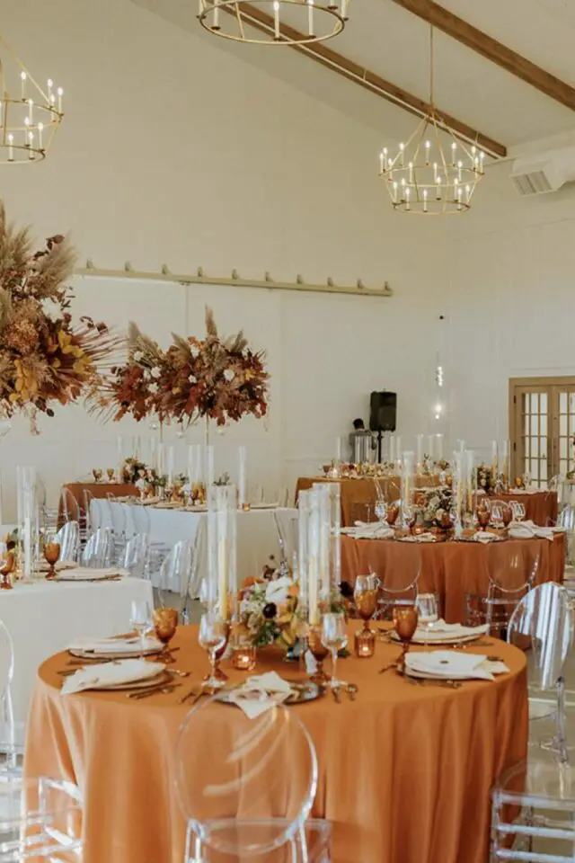 décoration mariage couleur orange exemple salle de réception mélange tables rondes et rectangulaire orange brûlé et blanc élégant nappe composition florale suspendue au plafond 